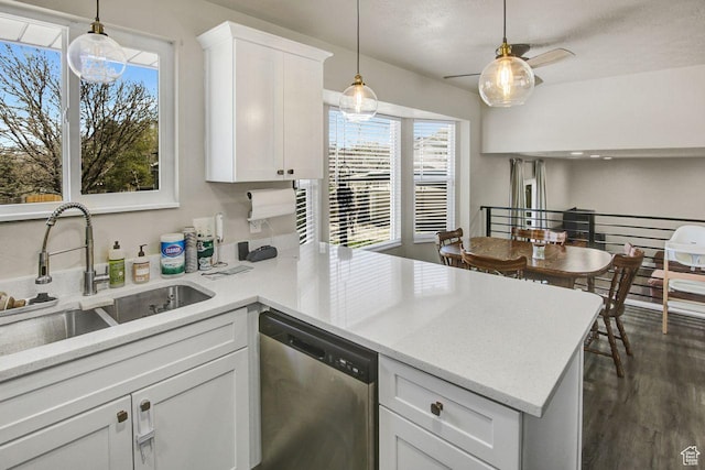 kitchen with a peninsula, white cabinets, decorative light fixtures, stainless steel dishwasher, and a sink
