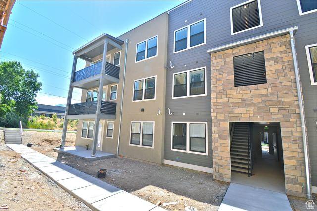 rear view of property featuring stucco siding and stone siding
