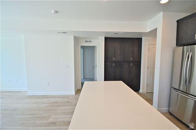 kitchen with dark brown cabinets, baseboards, freestanding refrigerator, and light wood finished floors