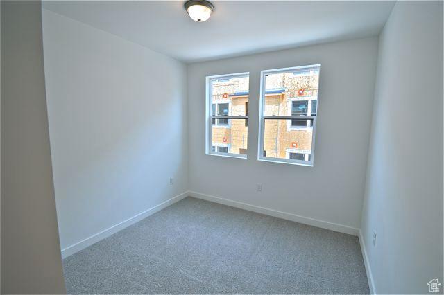 spare room featuring carpet floors and baseboards