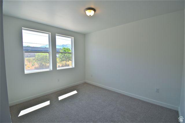 spare room featuring carpet flooring and baseboards