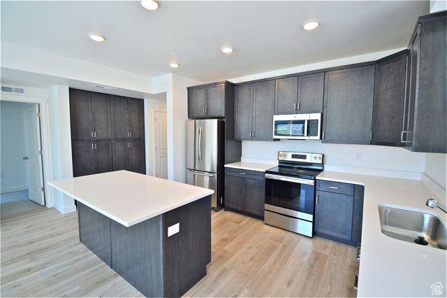 kitchen with light wood-style floors, appliances with stainless steel finishes, a sink, and visible vents