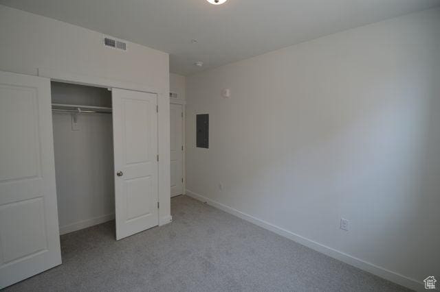 unfurnished bedroom with a closet, baseboards, electric panel, carpet floors, and visible vents