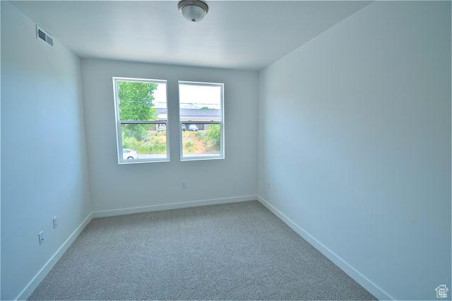 spare room with carpet flooring, visible vents, and baseboards