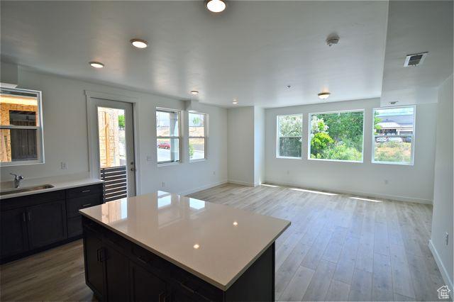 kitchen with light wood-type flooring, visible vents, light countertops, and a sink