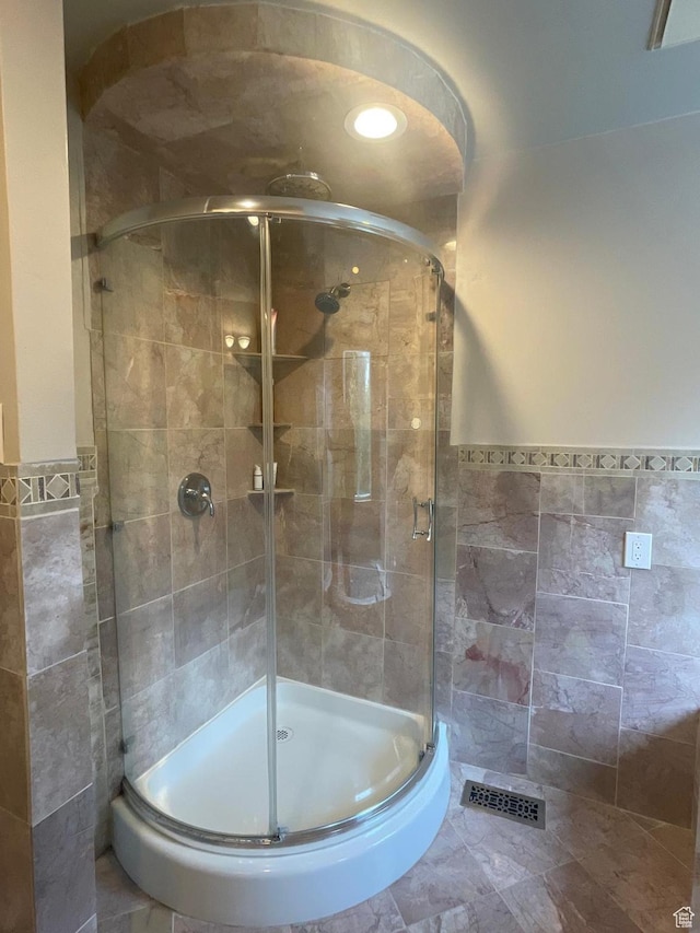 bathroom with visible vents, tile walls, and a stall shower