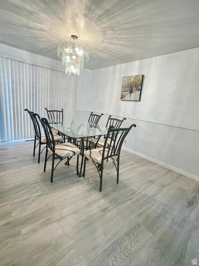 dining space with a chandelier, wood finished floors, and baseboards