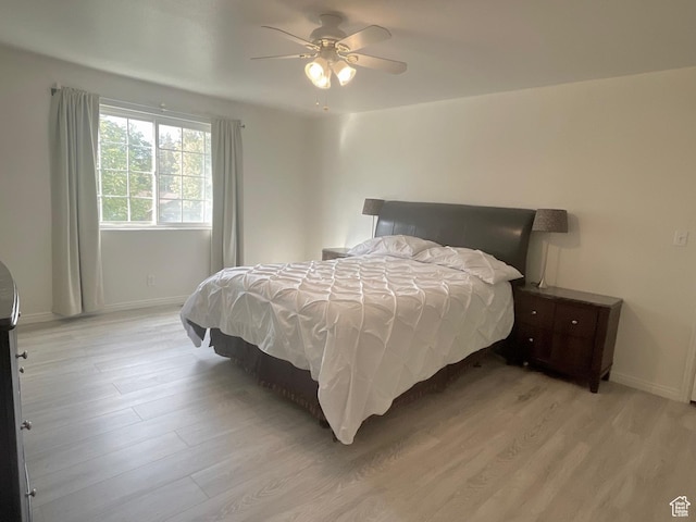 bedroom with light wood-type flooring, baseboards, and a ceiling fan