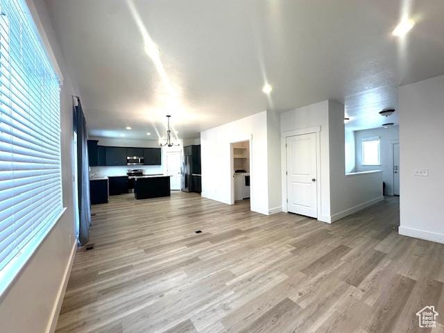 122 W 930 S, Tremonton, UT 84337 - unfurnished living room with light wood-style flooring, an inviting chandelier, and baseboards