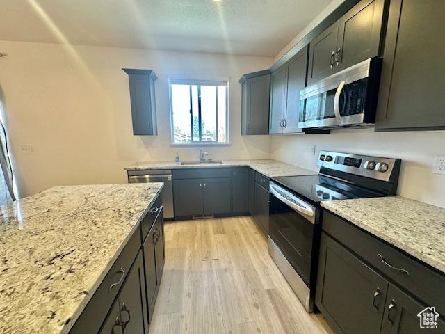 122 W 930 S, Tremonton, UT 84337 - kitchen with stainless steel appliances, light stone countertops, light wood-type flooring, and a sink