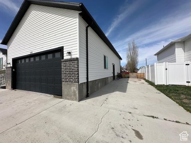 122 W 930 S, Tremonton, UT 84337 - view of home's exterior featuring driveway, a garage, fence, and brick siding