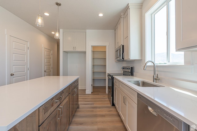 1038 W 2260 S Unit 105, Nibley, UT 84321 - kitchen featuring stainless steel appliances, light wood-type flooring, light countertops, recessed lighting, and hanging light fixtures