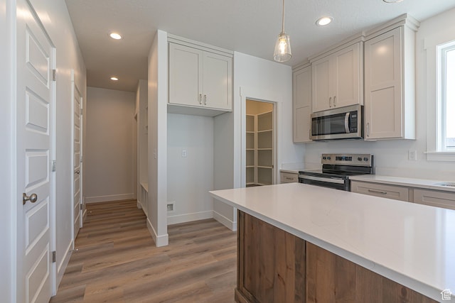 1038 W 2260 S Unit 105, Nibley, UT 84321 - kitchen featuring appliances with stainless steel finishes, light wood-style flooring, light countertops, recessed lighting, and hanging light fixtures