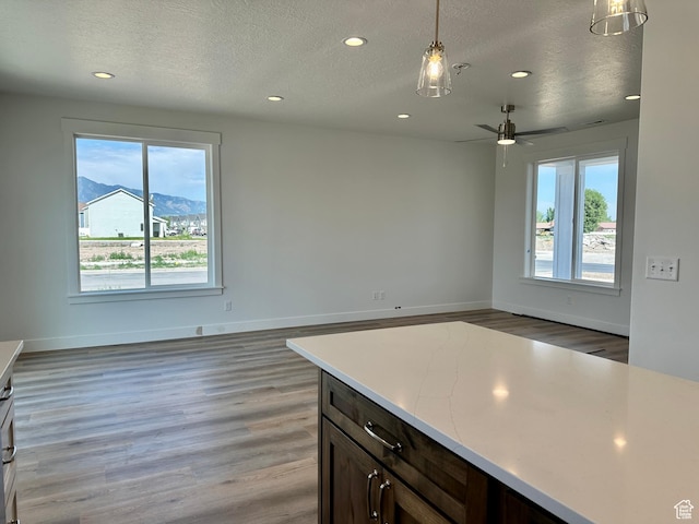 1038 W 2260 S Unit 105, Nibley, UT 84321 - kitchen featuring recessed lighting, a textured ceiling, light wood finished floors, light countertops, and pendant lighting