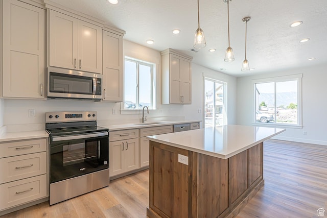 1038 W 2260 S Unit 105, Nibley, UT 84321 - kitchen with appliances with stainless steel finishes, light wood-style flooring, recessed lighting, a kitchen island, and light countertops