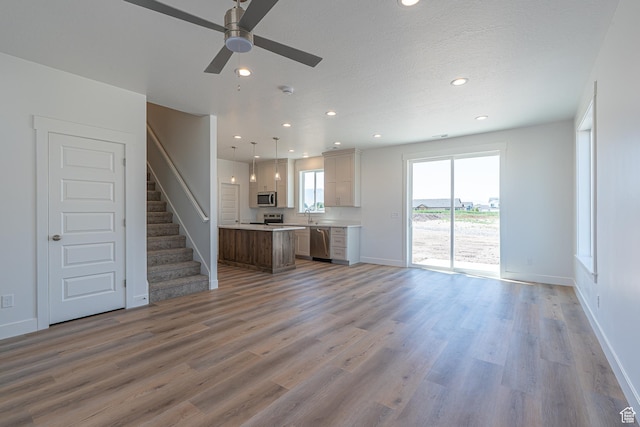 1038 W 2260 S Unit 105, Nibley, UT 84321 - unfurnished living room featuring recessed lighting, light wood-style floors, ceiling fan, and stairway