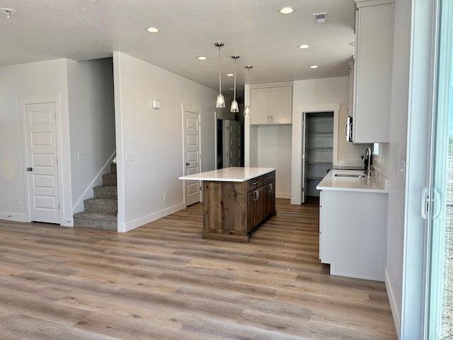 1038 W 2260 S Unit 105, Nibley, UT 84321 - kitchen featuring light wood-type flooring, a center island, recessed lighting, light countertops, and white cabinets