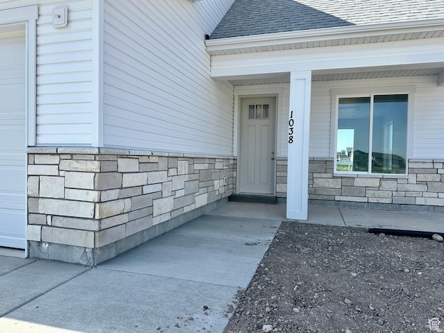 1038 W 2260 S Unit 105, Nibley, UT 84321 - doorway to property with stone siding, a shingled roof, and covered porch