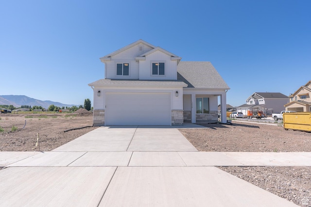 1038 W 2260 S Unit 105, Nibley, UT 84321 - view of front of property featuring driveway, a garage, stone siding, a porch, and a mountain view