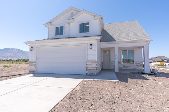 1038 W 2260 S Unit 105, Nibley, UT 84321 - view of front of property with stone siding, driveway, covered porch, an attached garage, and a mountain view