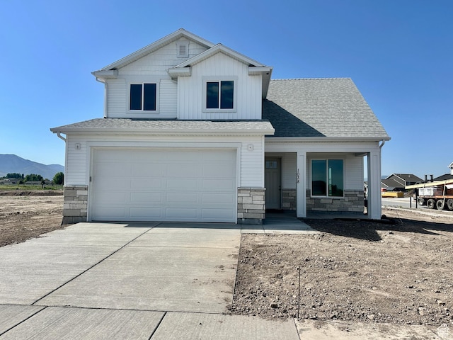 1038 W 2260 S Unit 105, Nibley, UT 84321 - view of front facade featuring concrete driveway, stone siding, an attached garage, and a porch