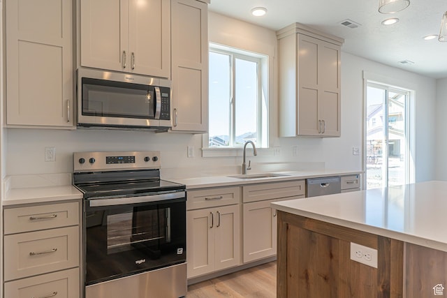 1038 W 2260 S Unit 105, Nibley, UT 84321 - kitchen featuring stainless steel appliances, light countertops, light wood-type flooring, and recessed lighting