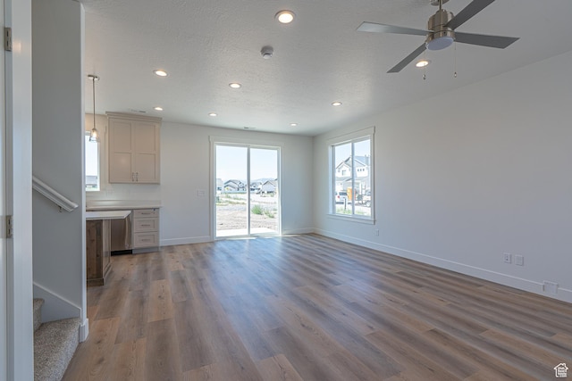 1038 W 2260 S Unit 105, Nibley, UT 84321 - unfurnished living room with recessed lighting, ceiling fan, wood finished floors, stairs, and a textured ceiling