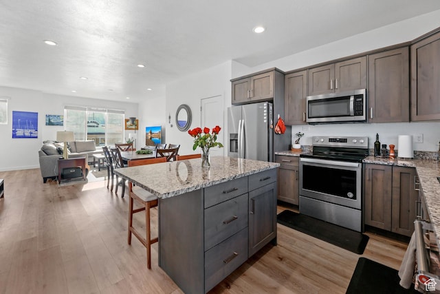 25 E Center Unit 10, North Salt Lake, UT 84054 - kitchen with light wood-type flooring, appliances with stainless steel finishes, light stone counters, and a breakfast bar