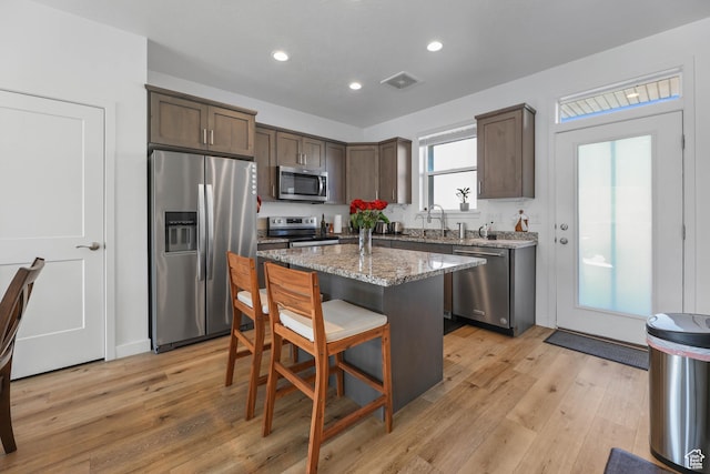 25 E Center Unit 10, North Salt Lake, UT 84054 - kitchen with light wood-type flooring, a breakfast bar, dark brown cabinets, visible vents, and stainless steel appliances