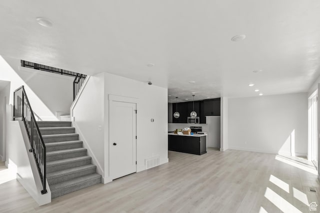 unfurnished living room featuring recessed lighting, stairway, light wood-style flooring, baseboards, and visible vents
