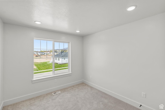 carpeted empty room featuring recessed lighting, visible vents, and baseboards