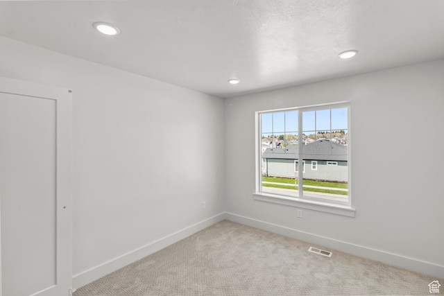 carpeted empty room featuring recessed lighting, visible vents, and baseboards