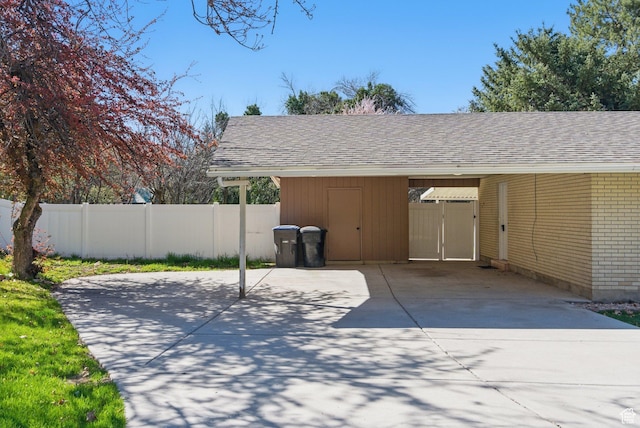 view of patio / terrace featuring concrete driveway, an attached carport, and fence
