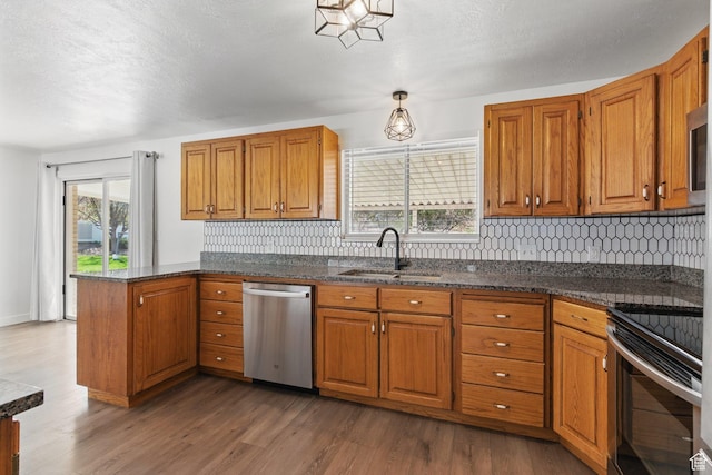 kitchen with stainless steel appliances, brown cabinets, a sink, and wood finished floors