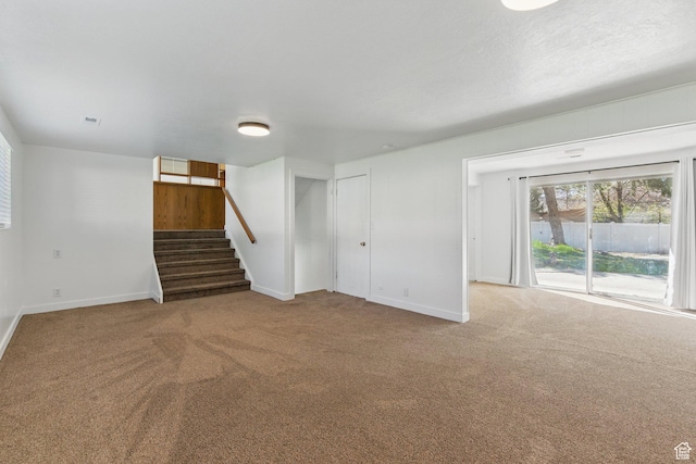 unfurnished living room with stairs, carpet, and baseboards