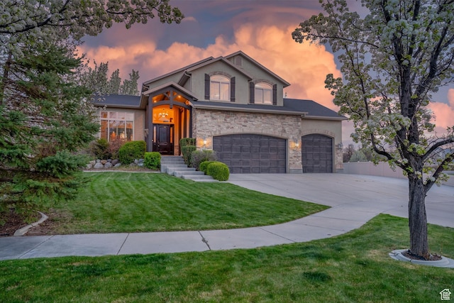 view of front of house featuring concrete driveway, stone siding, fence, a yard, and stucco siding