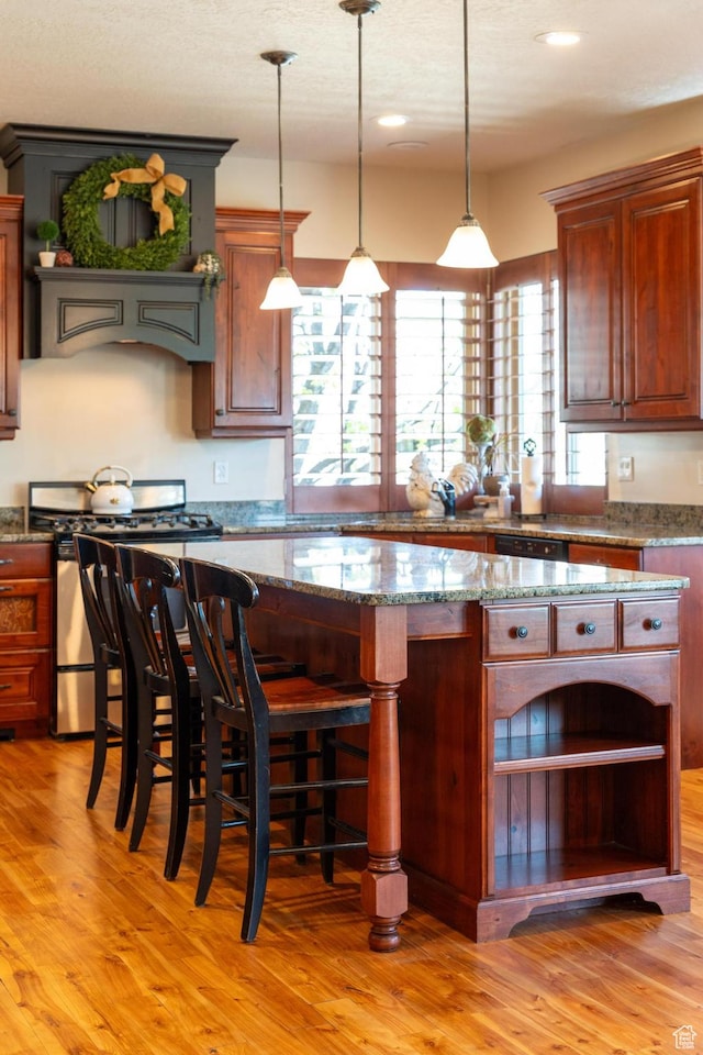 kitchen with stainless steel gas stove, light wood-type flooring, open shelves, and a kitchen island