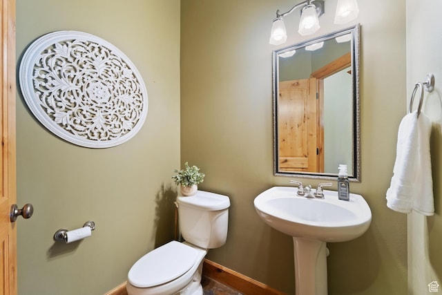 half bath featuring baseboards and toilet