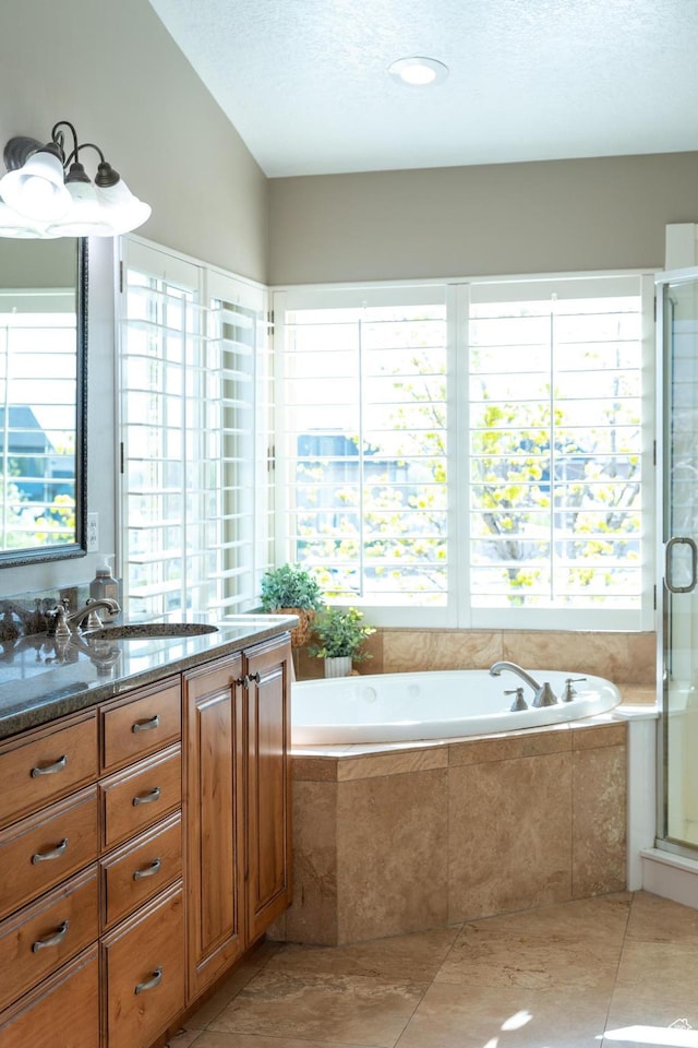 bathroom featuring a textured ceiling, a shower stall, a garden tub, and vanity