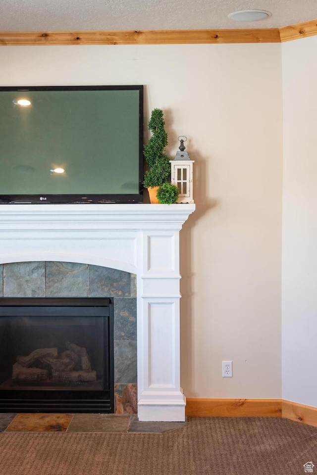 interior details featuring a tiled fireplace, baseboards, carpet, and ornamental molding