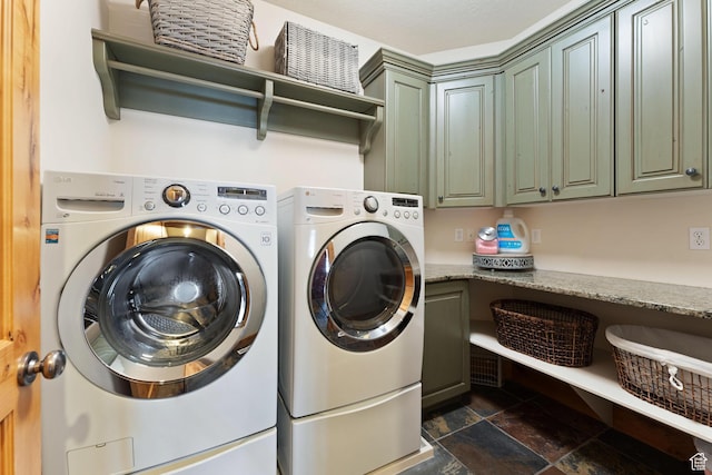 laundry area with stone tile flooring, separate washer and dryer, and cabinet space