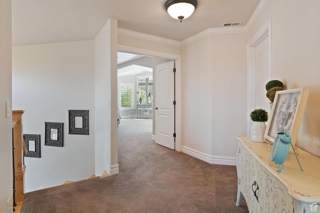 hallway with baseboards, crown molding, carpet flooring, and visible vents