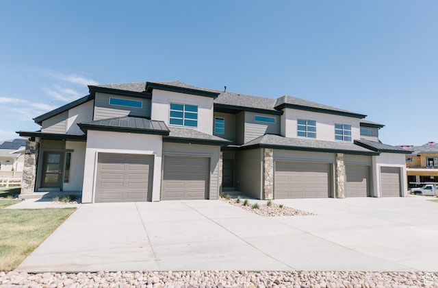 prairie-style house with an attached garage, stone siding, and concrete driveway