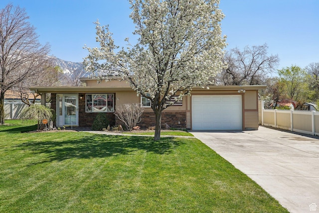 view of front facade with stucco siding, driveway, a front yard, a garage, and fence