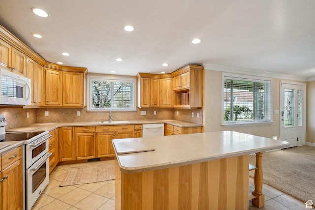 kitchen featuring recessed lighting, white appliances, a center island, light tile patterned flooring, and a sink