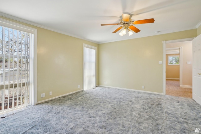 carpeted empty room with crown molding, baseboards, and a ceiling fan