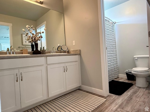 bathroom with a sink, toilet, wood finished floors, and baseboards