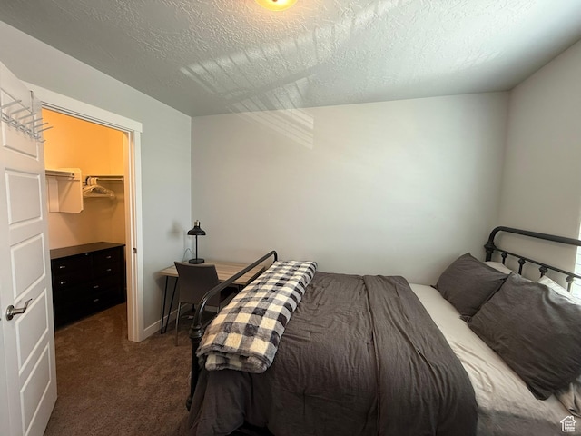 carpeted bedroom with a walk in closet and a textured ceiling