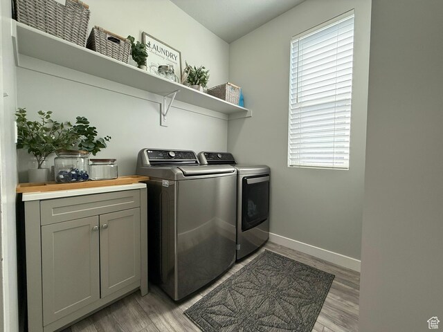 clothes washing area with washer and dryer, light wood-style floors, baseboards, and plenty of natural light
