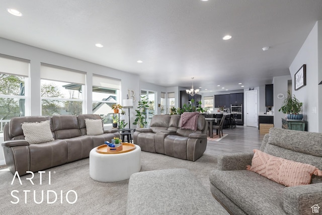 living room featuring light wood finished floors, a notable chandelier, and recessed lighting